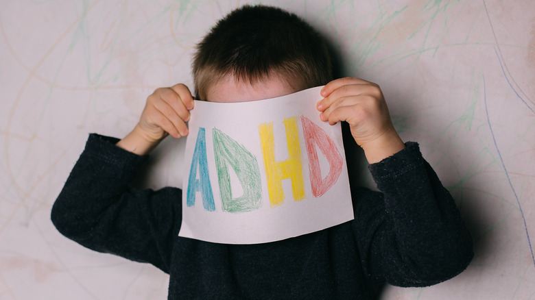 Child holding sign saying ADHD