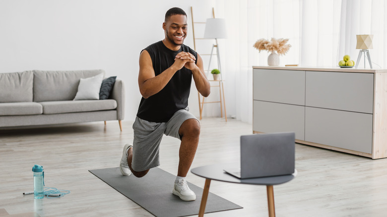 A man performs lunges at home