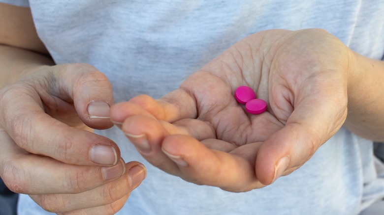 hand holding two ibuprofen tablets