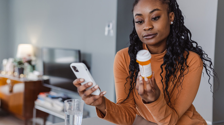Woman looking at medication bottle