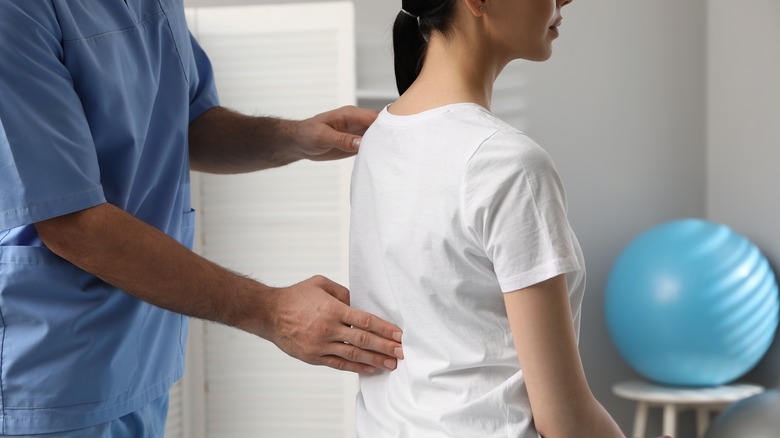 Healthcare practitioner placing hand on spine of patient