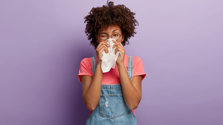 woman holding tissue and feeling sick