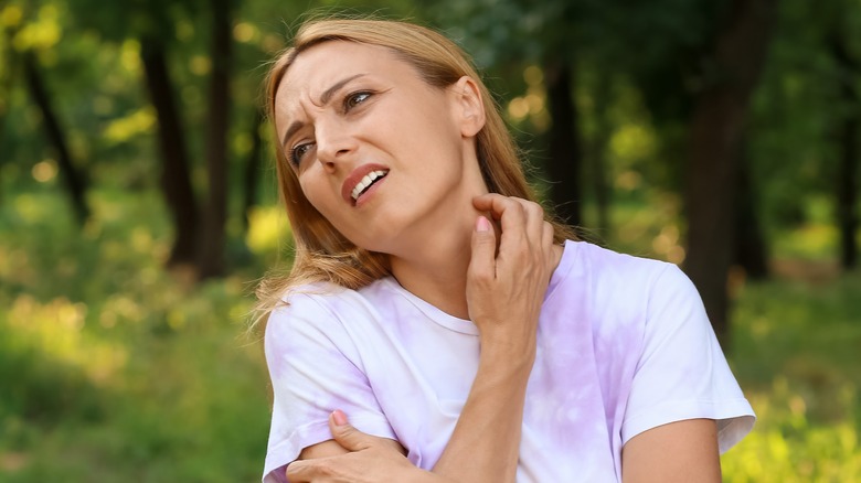 Woman scratching neck outside