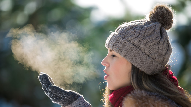 woman wearing hat and blowing out breath in cold outdoors
