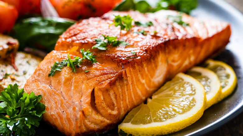 a piece of grilled salmon on a plate with lemon slices