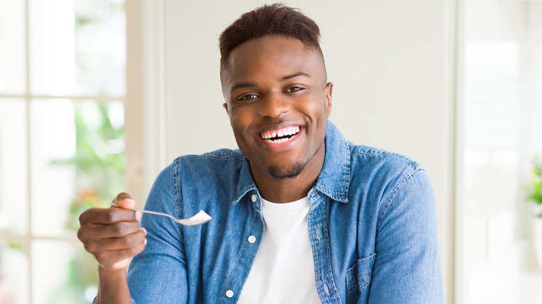 man holding spoon with yogurt