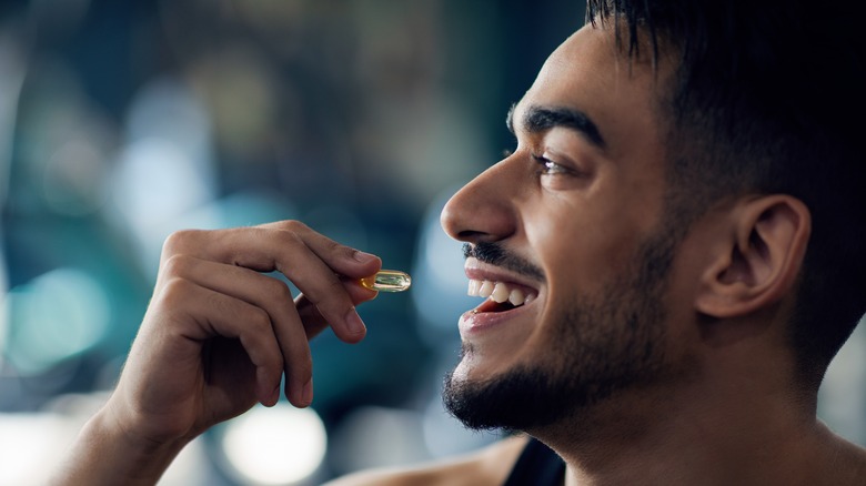 Smiling man taking vitamin supplement