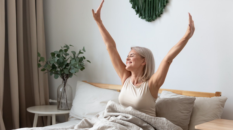 Woman stretching in bed waking up happy with energy