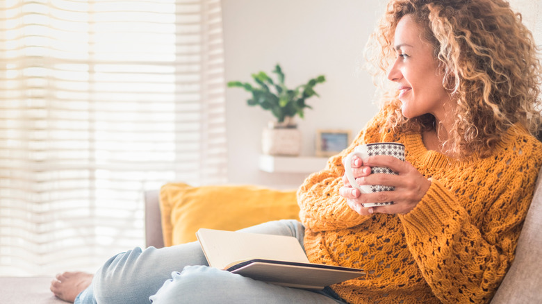 Smiling woman sitting on couch holding a mug of coffee