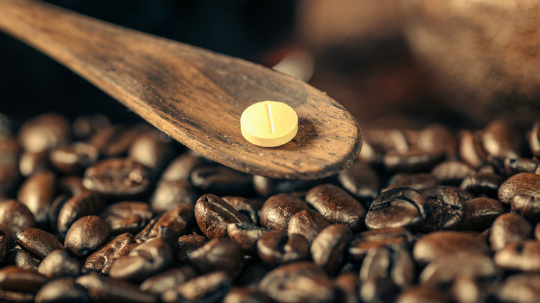 pill on a wooden spoon above coffee beans 