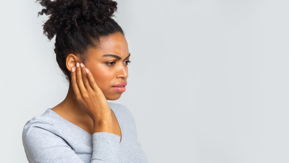 Black woman touching her ear in pain