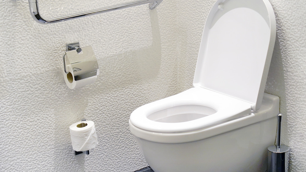 White toilet with white wall in background