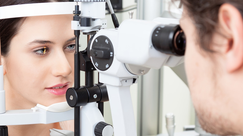 ﻿Eye doctor checking patient's eyes with a binocular slit-lamp