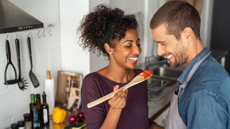 a young couple tasting tomato sauce