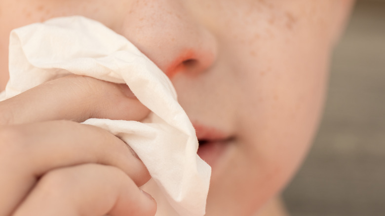 person holding tissue to irritated nose