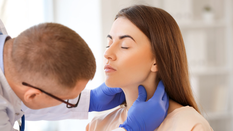 Doctor palpating thyroid of young woman