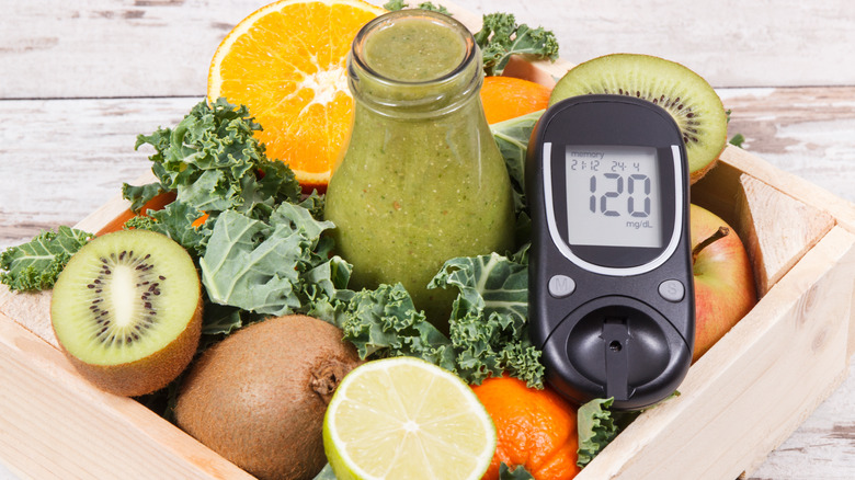 Glucometer with vegetables and fruits in the background