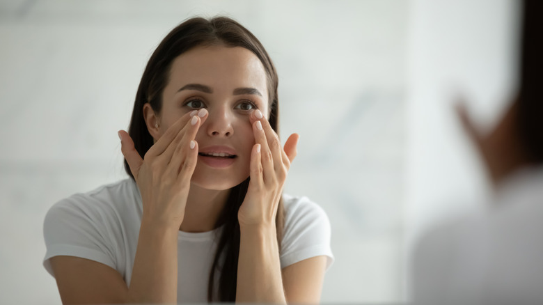 A woman applying under eye cream