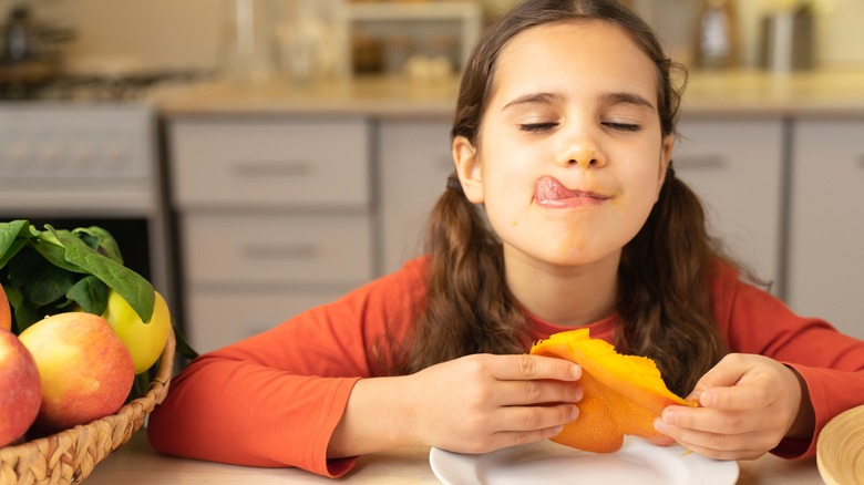 Young girl enjoying fresh mango