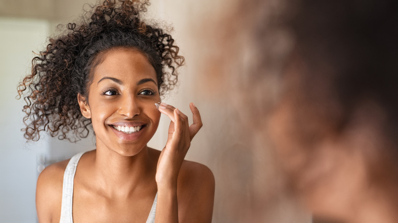 A woman applies face moisturizer