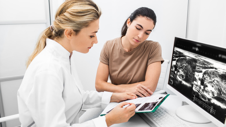 Radiologist consults woman in front of thyroid ultrasound images on screen