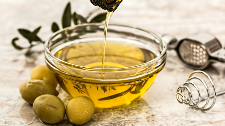 olive oil in a glass bowl with green olives