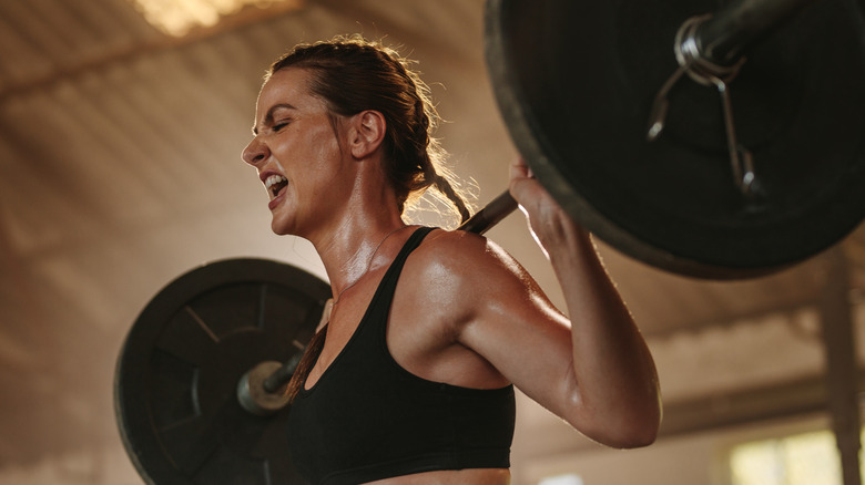 Yelling woman lifting barbell with weights