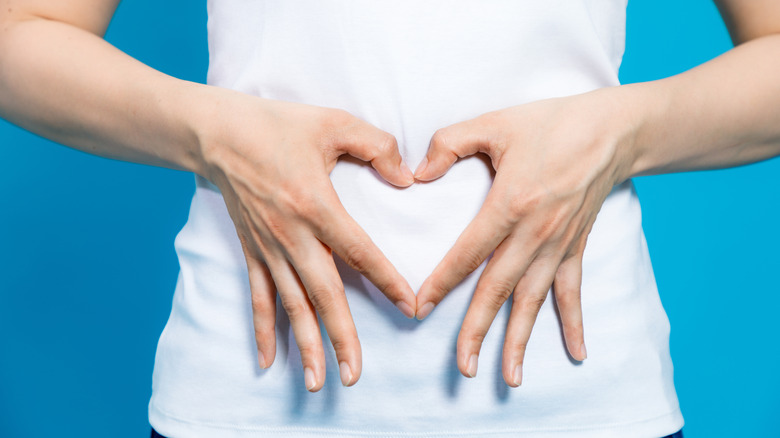 woman's abdomen framed by hands in heart shape