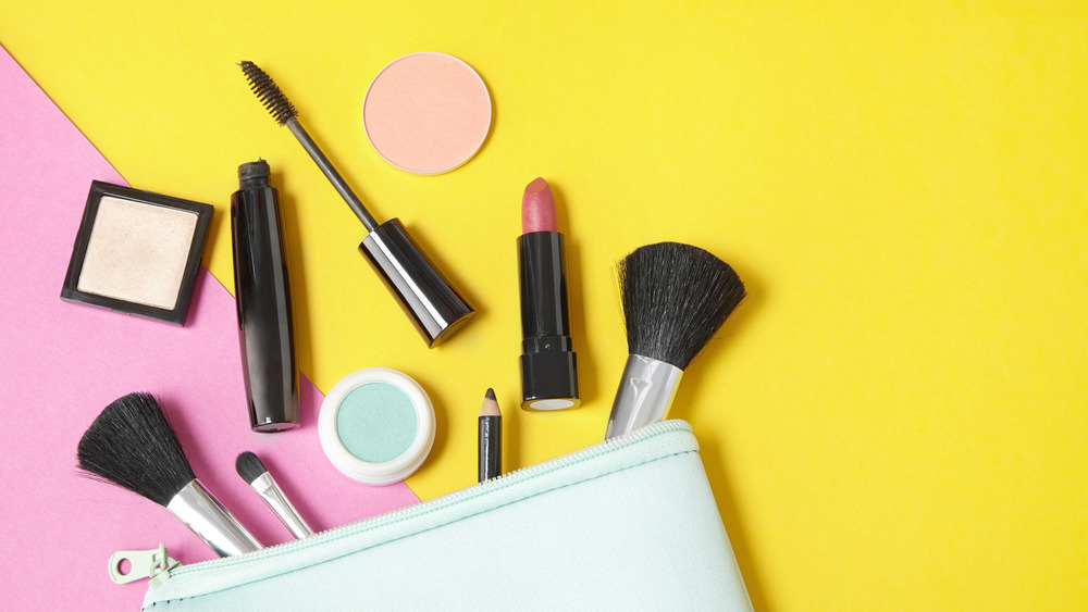 make-up products laid out on a bright pink and yellow background 