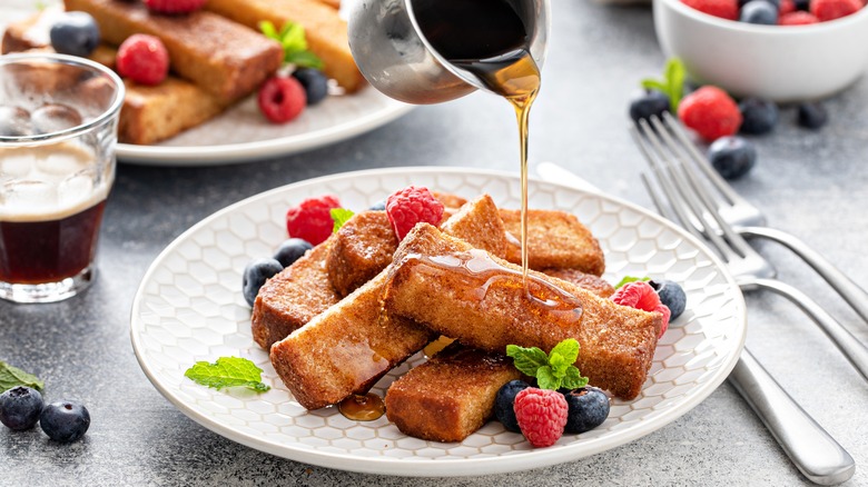 syrup drizzling over a plate of french toast sticks