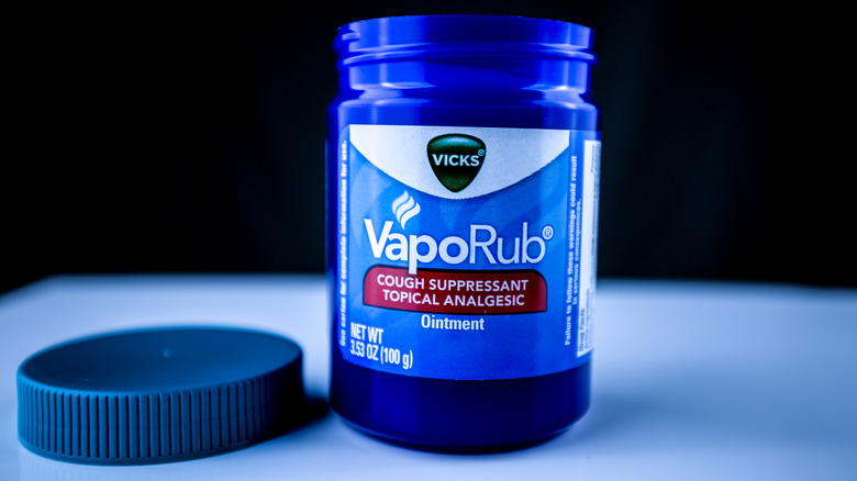 A blue jar of open Vicks with a black background 