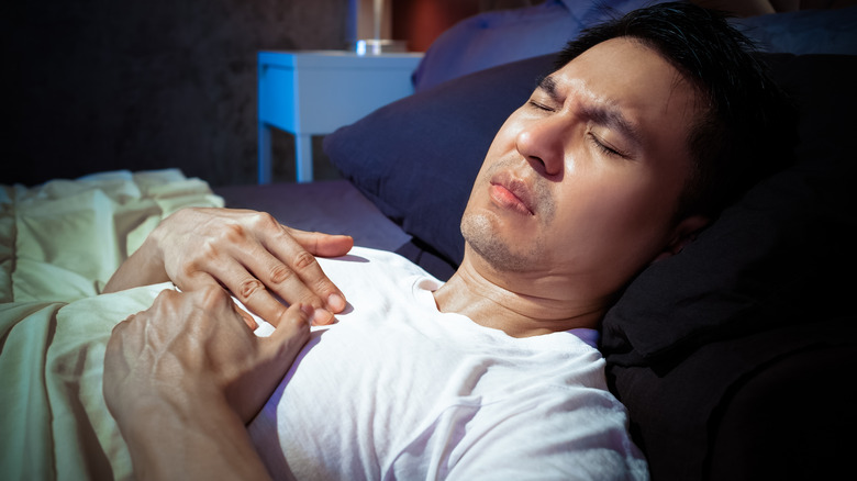 man in bed with chest pain 