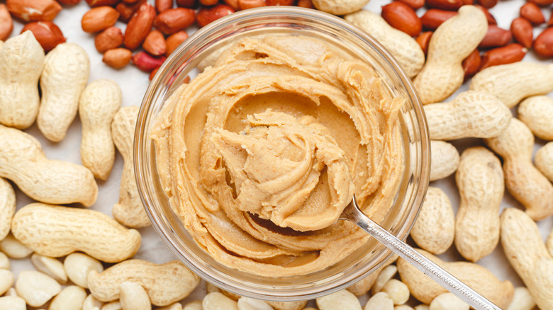 A peanut butter jar and different types of peanuts