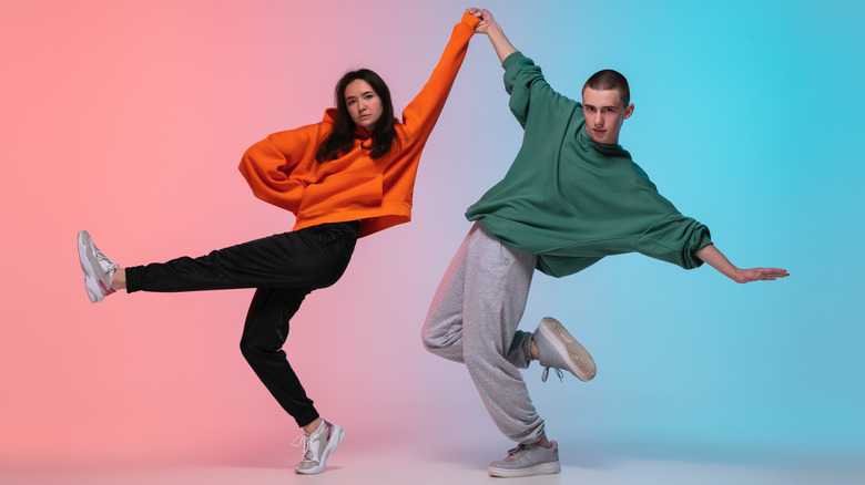 young couple dressed in loose clothing striking a dance pose 