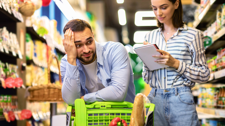 Couple going through shopping list while in grocery store