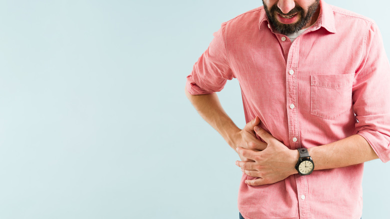 A man holds his stomach in pain