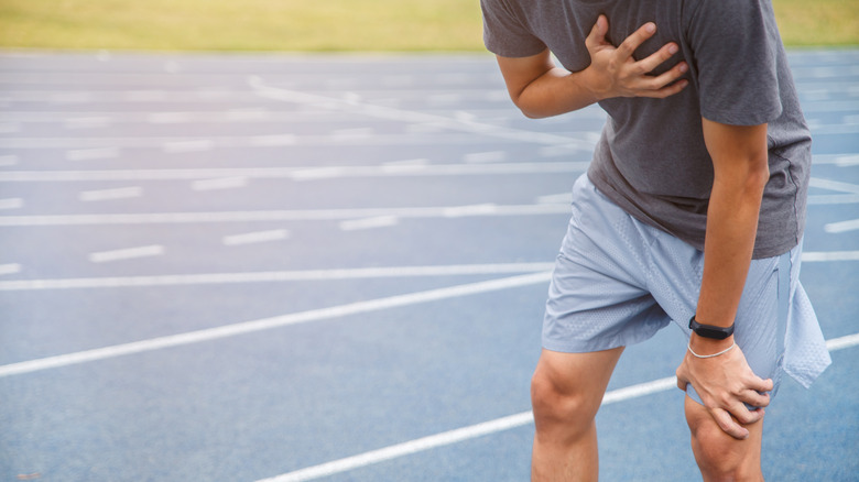 Man holding chest while running