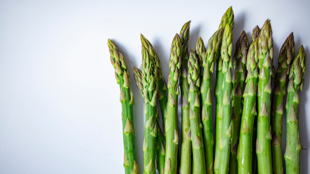 Stems of asparagus laid out on a neutral background
