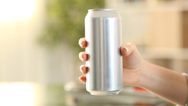 A woman holds a can of soda