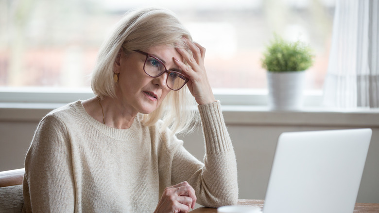 older woman sitting at her computer looking forgetful 