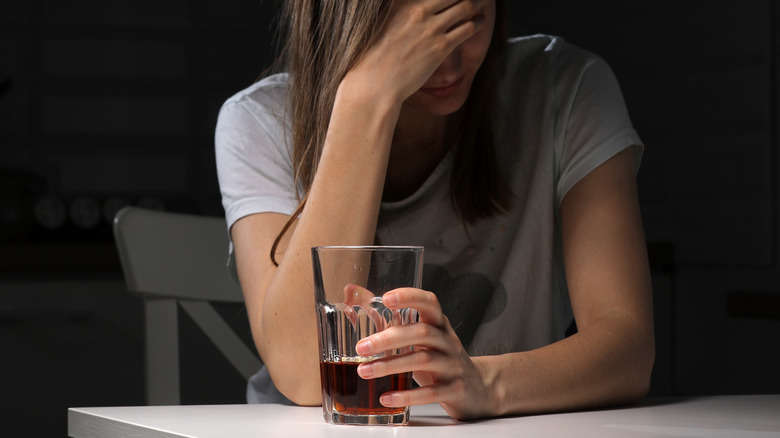 woman holding drink and looking sad