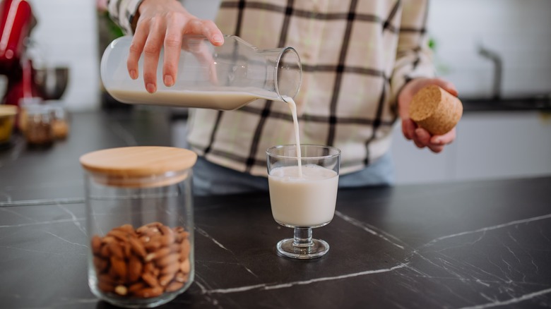 Hands pouring glass of almond milk