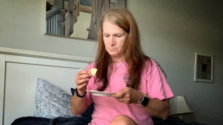 woman holding a piece of cheese while sitting on the bed