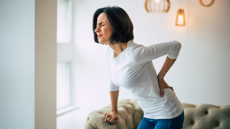 A woman holds her lower back in pain