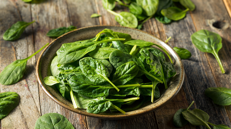 bowl of baby spinach on wooden table