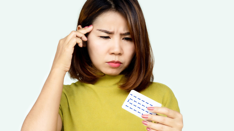 Woman looking confused holding birth control pill pack