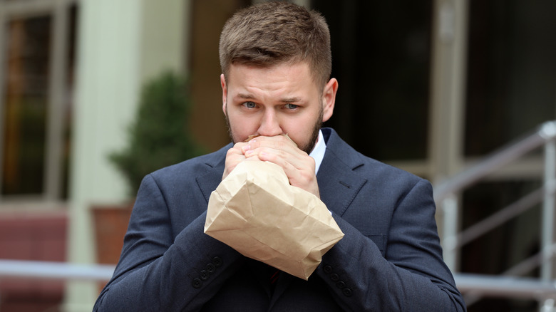 Businessman breathing into a paper bag outside
