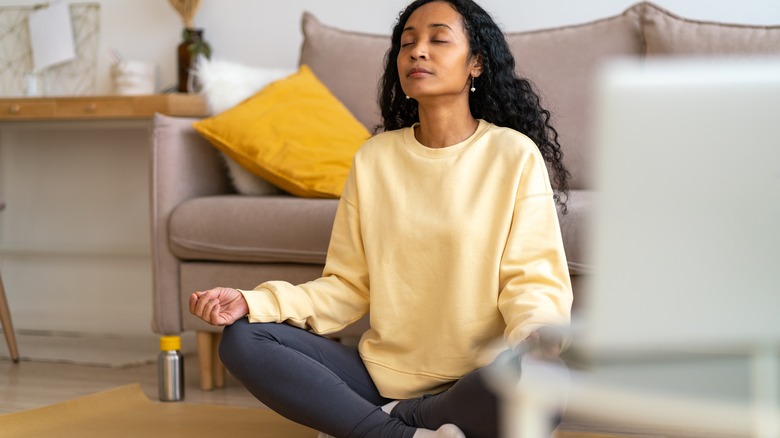 Woman sits cross-legged on yoga mat