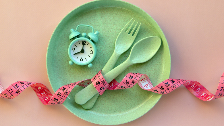 green plate with utensils, a clock and measuring tape