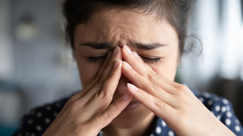 Woman holding nose while crying